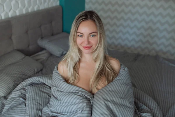 Χειμωνιάτικο πρωινό. Ένα σέξι κορίτσι τύλιξε τα παπλώματα της στο κρεβάτι. Κλινοσκεπάσματα και πρωιμότερο ξύπνημα στην εργασία — Φωτογραφία Αρχείου