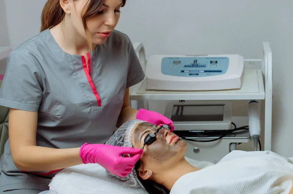 Zbliżenie procedury obierania węgla dla twarzy kobiety w średnim wieku. Laser pulsuje czystą skórą. Proces fototermolizy, ocieplenia, peelingu laserowego węgla. Odmładzanie skóry twarzy, leczenie kosmetologiczne. — Zdjęcie stockowe