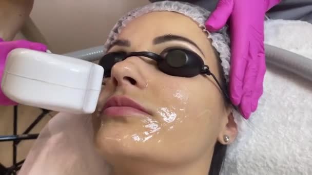 D'en haut de jeune cliente détendue se faisant masser le visage par échographie SMAS avec équipement professionnel dans un centre de beauté. — Video
