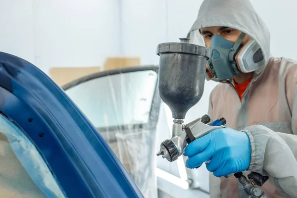 Automóvel reparador pintor mão em luva protetora com pulverizador de aerógrafo pintura corpo do carro na câmara de pintura . — Fotografia de Stock