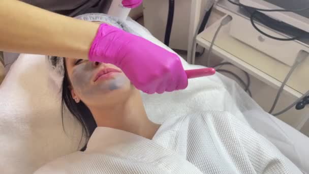 Косметик надевает маску на лицо женщины — стоковое видео