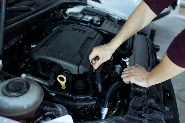 Un automóvil masculino está inspeccionando el motor de los autos. Servicio de coches y reparación de automóviles — Foto de Stock
