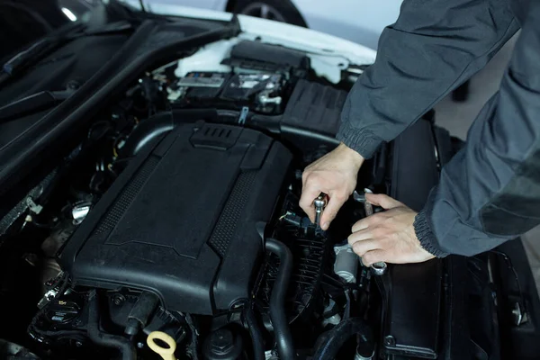 Un automóvil masculino está inspeccionando el motor de los autos. Servicio de coches y reparación de automóviles — Foto de Stock