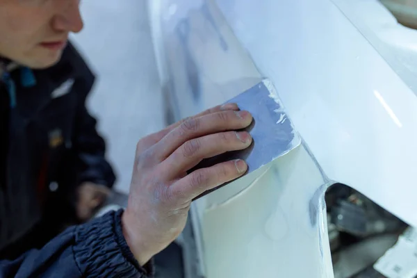 Reparação do corpo do carro, colocando fechar o trabalho após o acidente, trabalhando lixar primer antes de pintar. , O mecânico reparar o carro, Usando massa de vidraceiro de plástico, Prepare a superfície para pintura por pulverização. — Fotografia de Stock