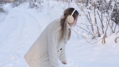 girl in the winter walks and has fun in the fresh air. cheerful excited woman throws snow and rejoices in flying snowflakes on a sunny frosty winter day