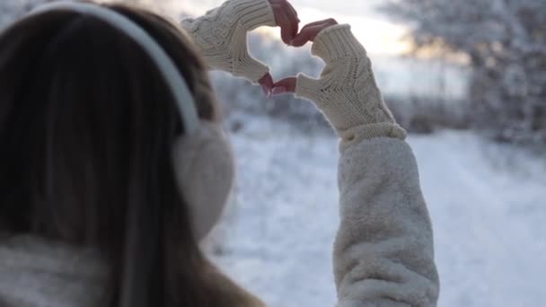 Female hands in winter gloves in the shape of a heart symbol, the concept of lifestyle and feelings, light nature on the background — Stockvideo