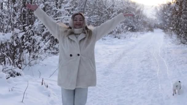 Winter holidays. A girl in a snowy forest outside jumps with happiness and laughs. Joy to the first snow — Wideo stockowe