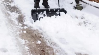 Karları kaldırmaya yakın çekim. Büyük kafesli bir adam dışarıda kar temizliyor.