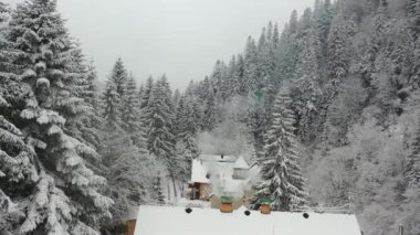 Hava manzaralı. Dağlarda ahşap bir ev. Kışın bacadan duman çıkıyor.