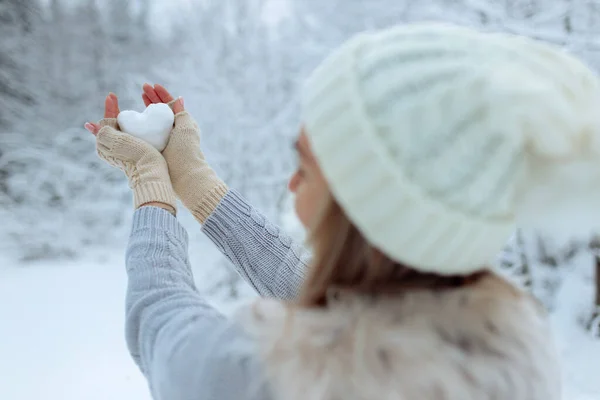 Eu gosto do inverno. Retrato de uma menina feliz segurando um coração nevado em sua mão durante o inverno. Dia dos Namorados. — Fotografia de Stock