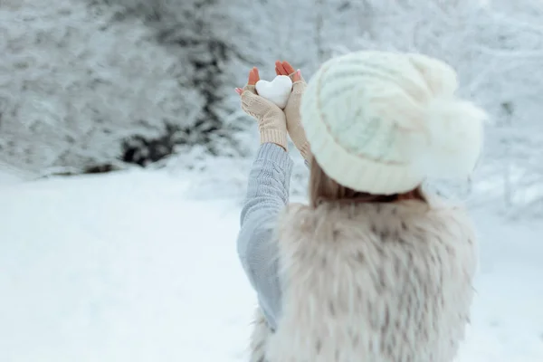 Eu gosto do inverno. Retrato de uma menina feliz segurando um coração nevado em sua mão durante o inverno. Dia dos Namorados. — Fotografia de Stock