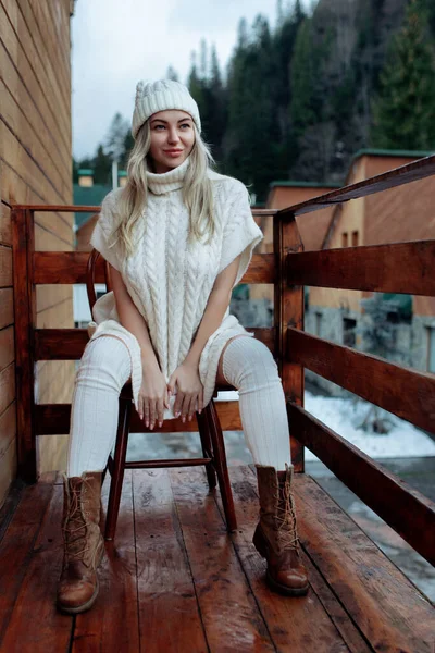 Сексуальна дівчина в білому светрі і панчохи на балконі захоплюються красою природи. шерстяний одяг і капелюх на красивій блондинці — стокове фото