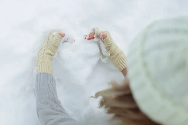 Close-up Coração de neve nas mãos em luvas de malha no fundo da cobertura de neve. Dia dos Namorados — Fotografia de Stock