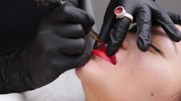 Cosmetoloog maakt permanente make-up op een vrouwengezicht. Specialist brengt een tattoo aan op de lippen van de patiënt close-up — Stockvideo