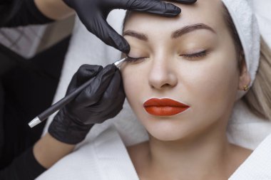 Kalıcı makyaj. Kozmetik uzmanı, göz dövmesi uygulaması için müşterilerin göz kapaklarına bir görünüm uygular.