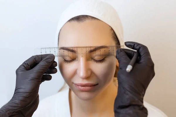 El amo permanente del maquillaje de la ceja aplica el contorno con el hilo en la ceja de los clientes — Foto de Stock