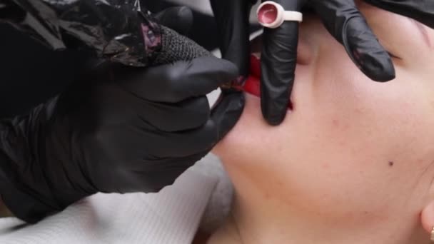 Cosmetoloog maakt permanente make-up op een vrouwengezicht. Specialist brengt een tattoo aan op de lippen van de patiënt close-up — Stockvideo