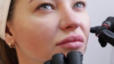 Kozmetik uzmanlarının salonunda dudaklarında kalıcı makyajı olan genç bir kadın. Kalıcı makyaj dövmesi. Kırmızı dudaklı bir çizgi çiz