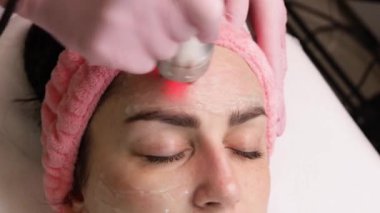 Kozmetik uzmanı biyokaldırma işlemi yapıyor. Cildin gençleşmesi, yaşlanmayı önlemesi, kadının çekici bir yüz bakımı görmesi. Modern klinikte donanım kozmetolojisi. 