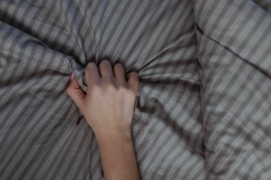 Bir kadın neşe içinde çarşafı sıkar. Bir kadında parlak bir orgazm, seksten ve ilk okşamalardan.