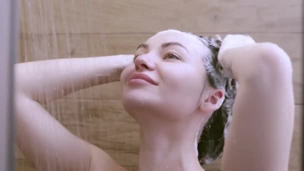 美しい裸の若い女性は彼女の髪を洗浄し バスルームでシャワーを浴びながらシャンプーを使用 — ストック動画