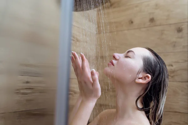 正在洗澡的女人享受着泼洒在她身上的水 闭着眼睛不让她放松 — 图库照片