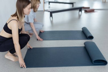 Stüdyoda egzersiz yapmadan önce mavi yoga ya da spor minderi seren çekici bir genç kadının yakın çekimi. Sağlıklı yaşam tarzı. 