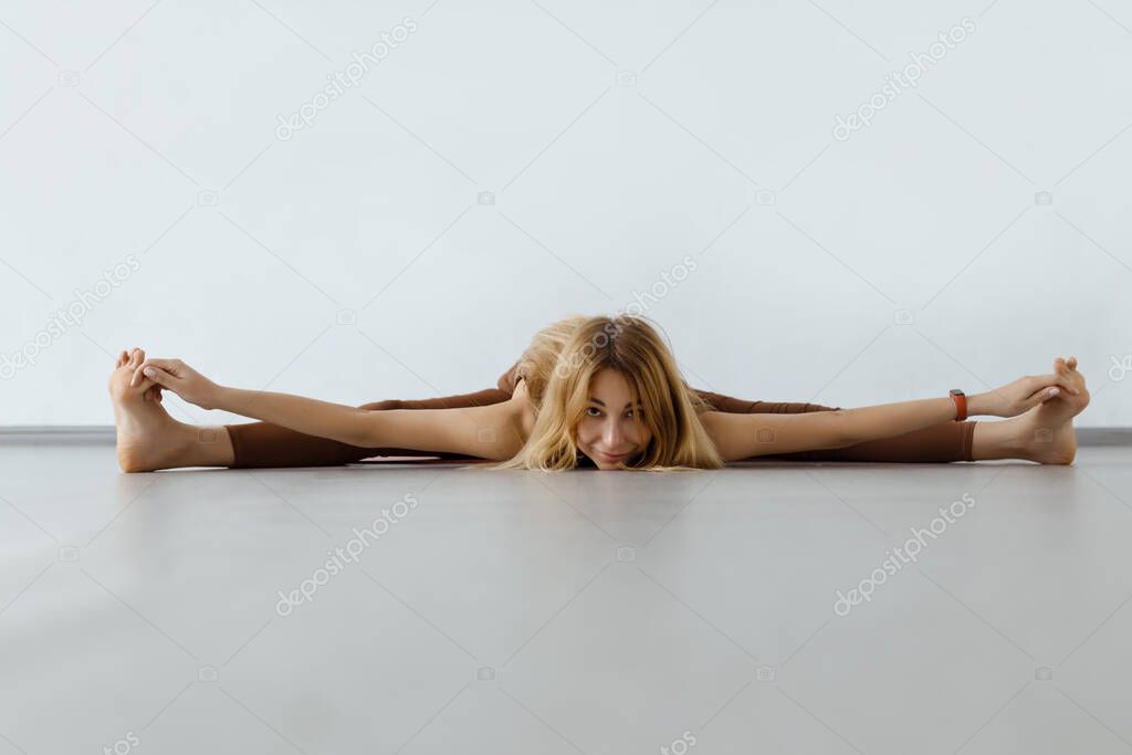 Young attractive fitness woman performing twine ,Upavista Konasana. 