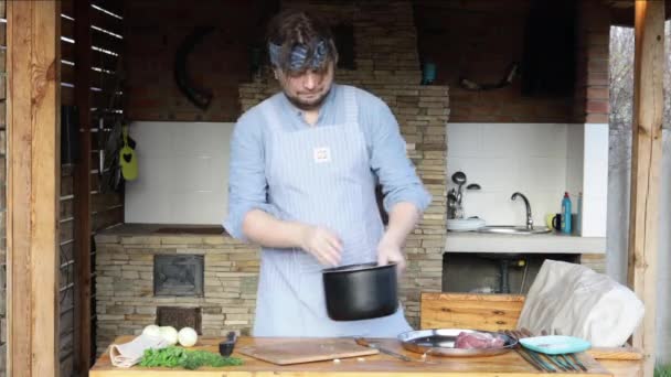 エプロンの男がバーベキューの肉が面白い踊りをマリネします 暖炉のそばの料理人がステーキを作る — ストック動画