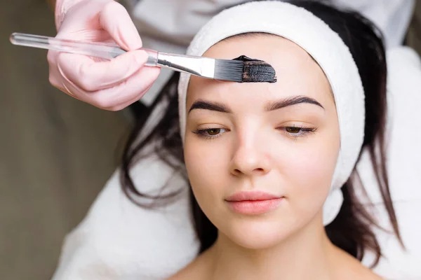 Cosmetologo Applicare Maschera Nera Sul Viso Bella Donna Indossando Guanti — Foto Stock