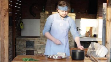 Önlüklü bir adam et parçalarını şişe bağlar ve şöminenin yanında kebap yapar. Gürcistan 'ın ulusal yemeği. 
