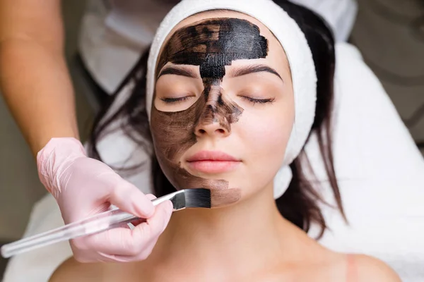 Cosmetoloog Toepassen Van Zwart Masker Mooie Vrouw Gezicht Dragen Van — Stockfoto