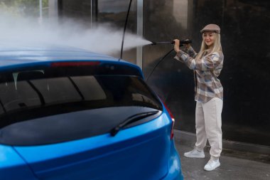 Otomobil yıkama istasyonunda köpüklü araba yıkayan bir kadın. Araba self-servis istasyonunu yıka.. 