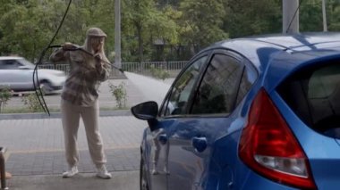 Otomobil yıkama istasyonunda köpüklü araba yıkayan bir kadın. Araba self-servis istasyonunu yıka.. 