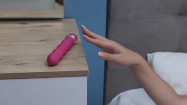 Young woman holding dildo on bed. Girl chooses a vibrator. lot of sex toys.