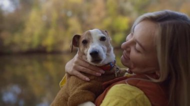 Tarlada bir köpeği öpen gülümseyen genç bir kadının portresi. Köpek sever stil kız yürürken köpeğine sarılıyor. Hayvan dostluğu kavramı. 