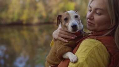 Tarlada bir köpeği öpen gülümseyen genç bir kadının portresi. Köpek sever stil kız yürürken köpeğine sarılıyor. Hayvan dostluğu kavramı. 