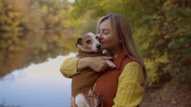 Tarlada bir köpeği öpen gülümseyen genç bir kadının portresi. Köpek sever stil kız yürürken köpeğine sarılıyor. Hayvan dostluğu kavramı. 
