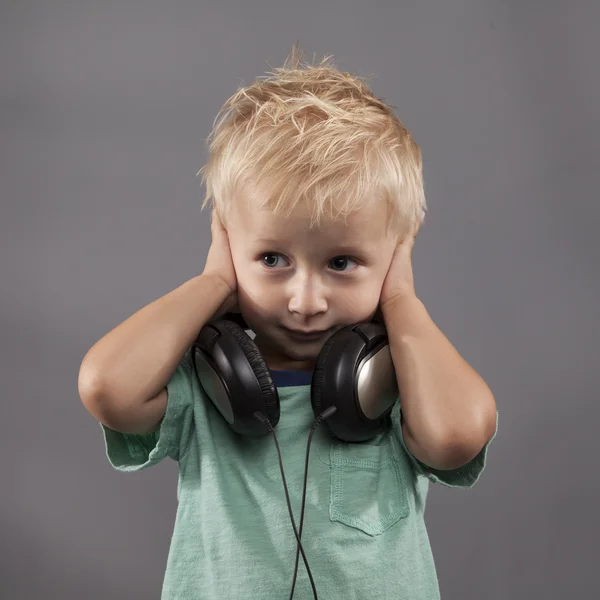 Um menino jovem segura as mãos sobre as orelhas — Fotografia de Stock