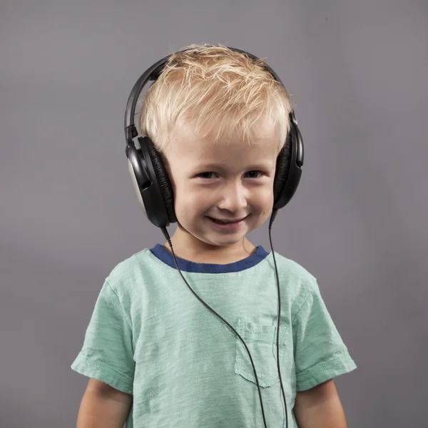 Menino sorri com fones de ouvido — Fotografia de Stock