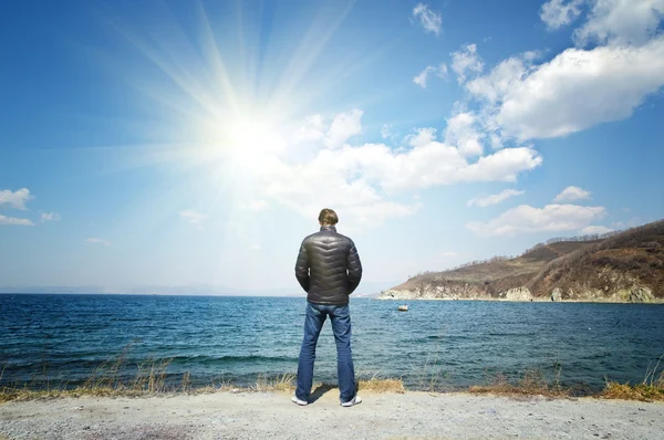 Muž stojí na pozadí moře a slunce — Stock fotografie