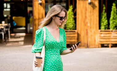 Şehrin arka planında keten rengi bir çantası olan güzel bir kadın..