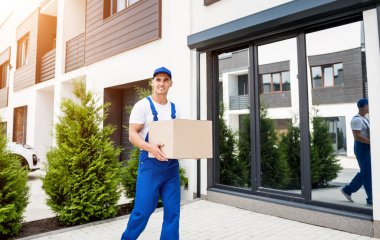 Genç teslimatçı elinde bir karton kutu tutuyor.