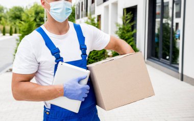 Koruyucu maske takan ve eldiven takan genç kurye karantina sırasında mal teslim ediyor.