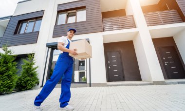 Genç teslimatçı elinde bir karton kutu tutuyor.