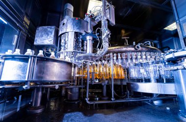 Modern içecek fabrikasında otomatik doldurma makinesi plastik PET şişelerine su doldurur.