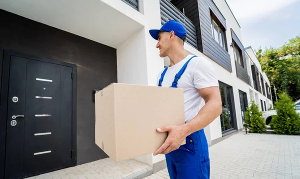 Junger Zusteller hält einen Karton in der Hand — Stockfoto