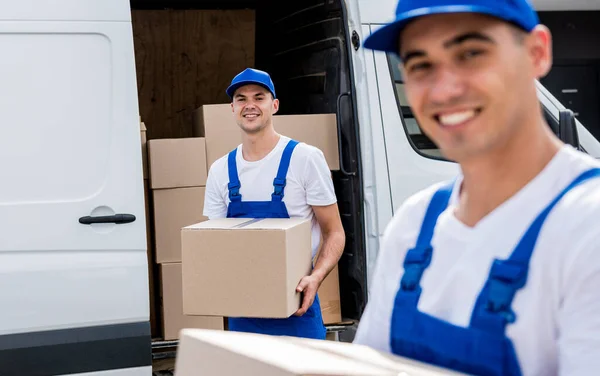 Dois trabalhadores da empresa de remoção descarregar caixas de microônibus em nova casa — Fotografia de Stock