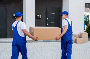 İki nakliye şirketi çalışanı minibüsten yeni eve kutular boşaltıyor.