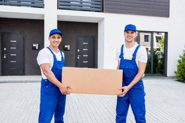 İki nakliye şirketi çalışanı minibüsten yeni eve kutular boşaltıyor.